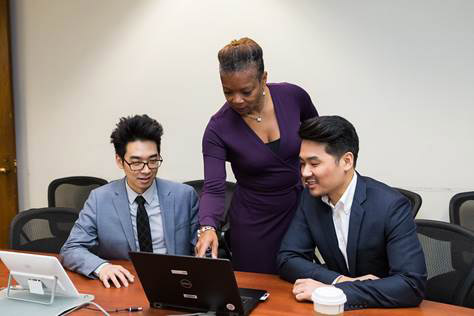 A group of people sitting at a desk Description automatically generated